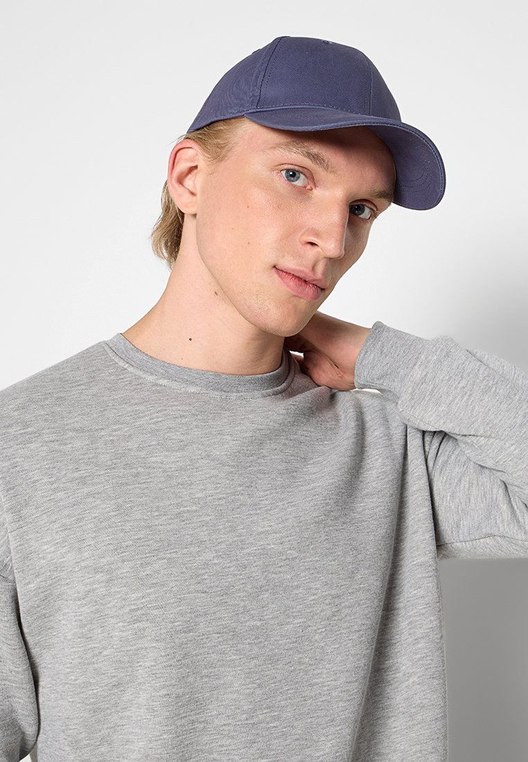 Szary sweatshirt z okrągłym dekoltem w połączeniu z granatową czapką. Oba elementy charakteryzują się gładką, czystą powierzchnią bez widocznych wzorów.