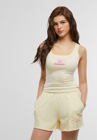 Heleroheline tank top roosa "fabulous" logoga, koos vastava šortsiga, mille vasakul jalal on liblikatikk.