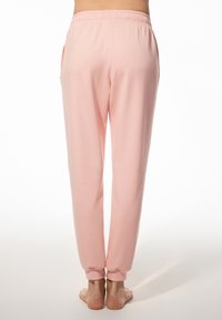 Lichtroze joggers gemaakt van zachte stof, met een relaxed fit, elastische tailleband en taps toelopende enkels. Geen zichtbare zakken of details.