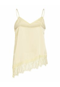 Camisole en satin couleur crème avec fines bretelles et bordure en dentelle festonnée le long de l'ourlet asymétrique.