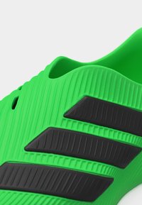 Kirkkaanvihreä liukuselkine, jossa on teksturoitu pinta ja kolme viistottua mustaa raitaa sivulla.