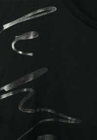 Černé tričko s texturovaným stříbrným abstraktním designem. Hladká látka s kulatým výstřihem, který zvýrazňuje kontrastní potisk.