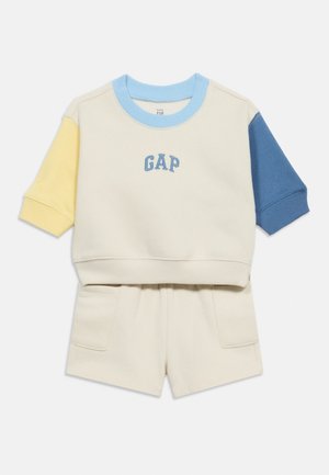 Tenue enfant couleur crème avec sweat-shirt à manches courtes bleu, jaune et manches bleues et short assorti avec poches avant.