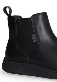 Stivaletto Chelsea in pelle nera con pannello elastico laterale, tabella sul tallone e etichetta di marca in tessuto sul lato.
