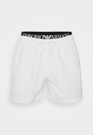Shorts de bain blancs avec une taille élastique noire portant le logo "EMPORIO ARMANI", fermeture à cordon de serrage et texture de tissu lisse.