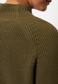 Olivgrüner, gerippter Strickpullover mit hohem Kragen und strukturiertem Finish, der eine eng anliegende Passform hat, die den Konturen des Halsausschnitts folgt.
