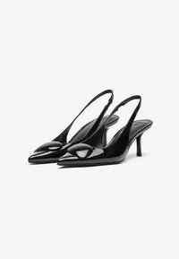 Fekete lakkbőr csúszó sarkú magassarkúk, hegyes orral és egyedi lekerekített részlettel elöl. A karcsú sarkak elegáns sziluettet biztosítanak.