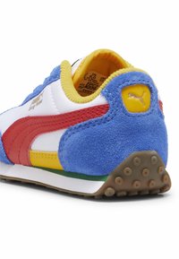 Zapatilla con parte superior de cuero blanca y roja, talón de ante azul, acentos amarillos y suela multicolor. Texturizada con una suela de goma.