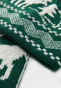 Bufanda de punto verde y blanca con patrones geométricos y tejido texturizado, con una trama suave y densa y detalles de costura visibles.