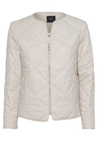 Veste matelassée beige clair avec encolure ronde, manches longues, fermeture éclair à l'avant et étiquette "Think Happy" sur la tirette.