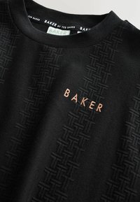 Schwarzer Sweatshirt mit strukturiertem schwarzen Muster und "BAKER" in Kupfer gestickt. Rundhalsausschnitt und glattes Strickmaterial.