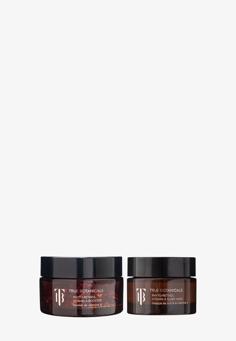 Deux bocaux en ambre avec des couvercles noirs étiquetés True Botanicals Phyto-Retinol Booster de Vitamine A et Masque de Nuit sur un fond blanc.