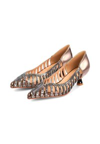 Zapatos de tacón bajo con punta afilada en un brillante oro rosa, con un diseño recortado, detalles en plata y una superficie texturizada; pequeño tacón negro.