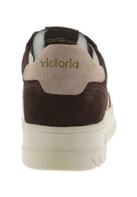 Sneaker in camoscio marrone con un accento in pelle beige sul tallone e scritte beige. Suola spessa in gomma bianca, costruzione robusta e dettagli cuciti.