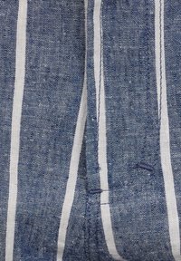 Blau gestreifter Stoff mit abwechselnden weißen Streifen. Das Material sieht strukturiert und gewebt aus und zeigt leichte Variationen in den Fadenfarben.