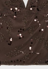 Tissu en mesh marron foncé avec des sequins et des perles noirs et métalliques formant des motifs floraux abstraits.