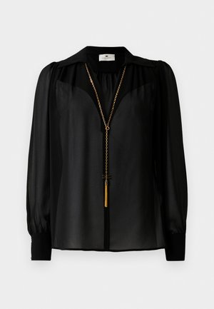 Fekete, áttetsző, hosszú ujjú blúz széles gallérral és arany láncnyaklánccal, amelynek a végén bojt pendant lóg elöl.