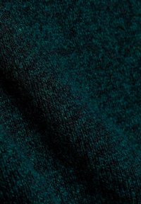 Tissu en laine vert foncé et noir avec une texture douce tricotée et des fibres visibles en vue rapprochée.