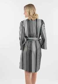 Ropa de rayas en blanco y negro con cinturón en la cintura, mangas largas y una textura ligera y suave. Presenta rayas verticales de diferentes anchos.