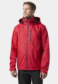 Czerwona wodoodporna kurtka z kapturem, przednim suwakiem i kieszenią na zamek błyskawiczny na piersi. Posiada elastyczne mankiety oraz gładkie, trwałe wykończenie materiału.