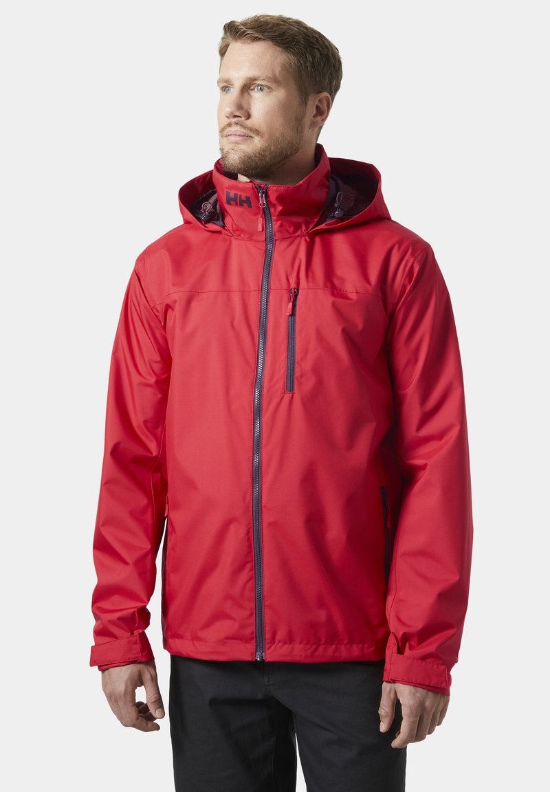 Czerwona wodoodporna kurtka z kapturem, przednim suwakiem i kieszenią na zamek błyskawiczny na piersi. Posiada elastyczne mankiety oraz gładkie, trwałe wykończenie materiału.