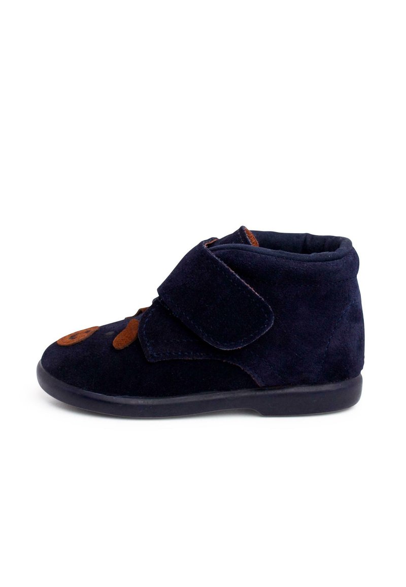 Stivale in suede blu scuro con dettagli marroni e una striscia in velcro. Forma della punta rotonda, colletto imbottito e suola flessibile in gomma nera.