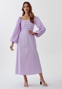 Lilac long dress with puff sleeves and square neckline, featuring pleated detailing on the bodice and a flowing skirt. Smooth fabric texture.