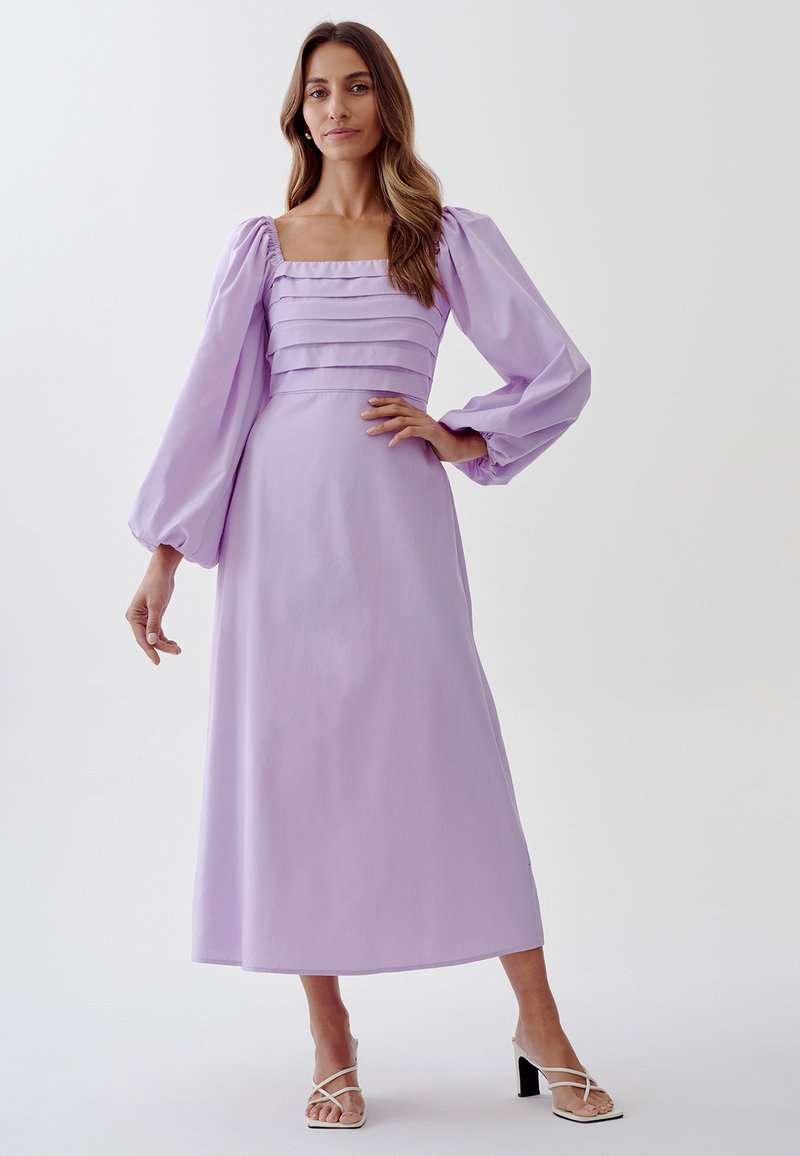 Lilac long dress with puff sleeves and square neckline, featuring pleated detailing on the bodice and a flowing skirt. Smooth fabric texture.