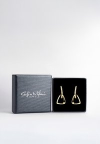 Guldtonade triangulära örhängen med texturerade öglor, presenterade i en svart, texturerad smyckesask med vit branding.