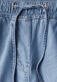 Szorty dżinsowe z elastyczną talią, jasnoniebieski kolor, detal ze sznurkiem oraz kieszeniami bocznymi. Gładka tekstura i swobodny styl.