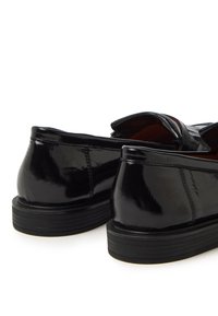 Zapatos de charol negros con una superficie lisa y brillante, con forma redondeada y una suela de goma duradera, diseñados para la comodidad.