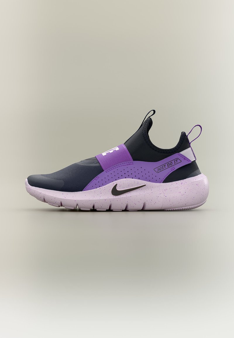 Chaussure de sport noire et violette à enfiler, avec une semelle blanche mouchetée, le logo Nike swoosh et le texte "Just Do It" sur la sangle latérale.