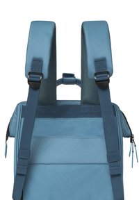 Zaino blu con spallacci imbottiti, clip regolabili, tessuto strutturato e manico superiore. Cerniera con tiranti blu, forma rettangolare.