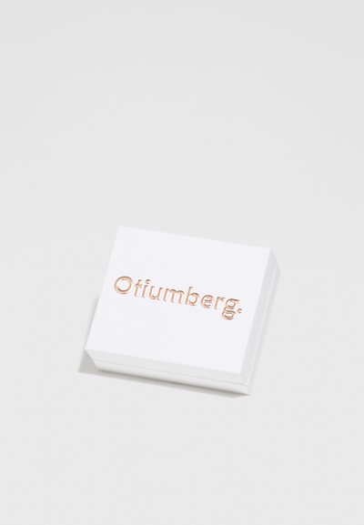 Valge ristkülikukujuline kast sileda pinnaga, millel on tõstetud roosakuldne kiri "Otiumberg" ülemisel pinnal.