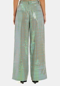 Wijduitlopende broek met een metallic glans, voorzien van een pastel ruitpatroon en een zachte textuur. Twee achterzakken en een hoge taille.