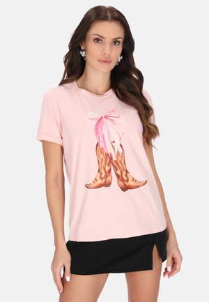 Lichtroze katoenen t-shirt met een grafiek van cowboylaarzen en een roze strik. Het shirt heeft opgerolde mouwen en een losse pasvorm.