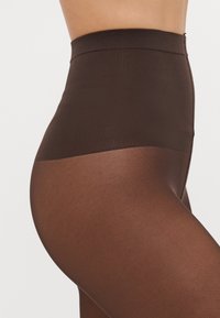 Brune høyt liv tights med en teksturert midjebånd og glatt benparti, med en matt finish og sømløst design.