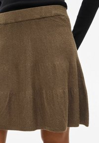 Jupe en tricot marron au design évasé et à taille côtelée, offrant une texture douce et un tissu léger.