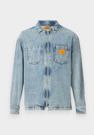 Lichtblauwe denim jas met een volledige rits aan de voorkant, twee borstzakken en een klein oranje Replay Inc. label op de rechterzak en de kraag.