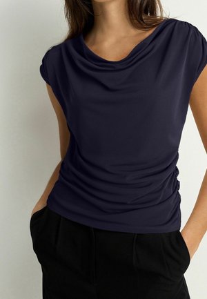 Granatowy top z krótkim rękawem z opuszczanym dekoltem i marszczeniem po bokach. Wykonany z gładkiej tkaniny, cechuje się luźnym krojem i miękką fakturą.