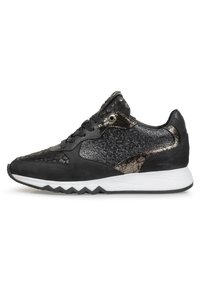 Sneaker nera con una parte superiore testurizzata adornata con accenti metallici, materiali in suede e sintetici, e suola bianca a zigzag.
