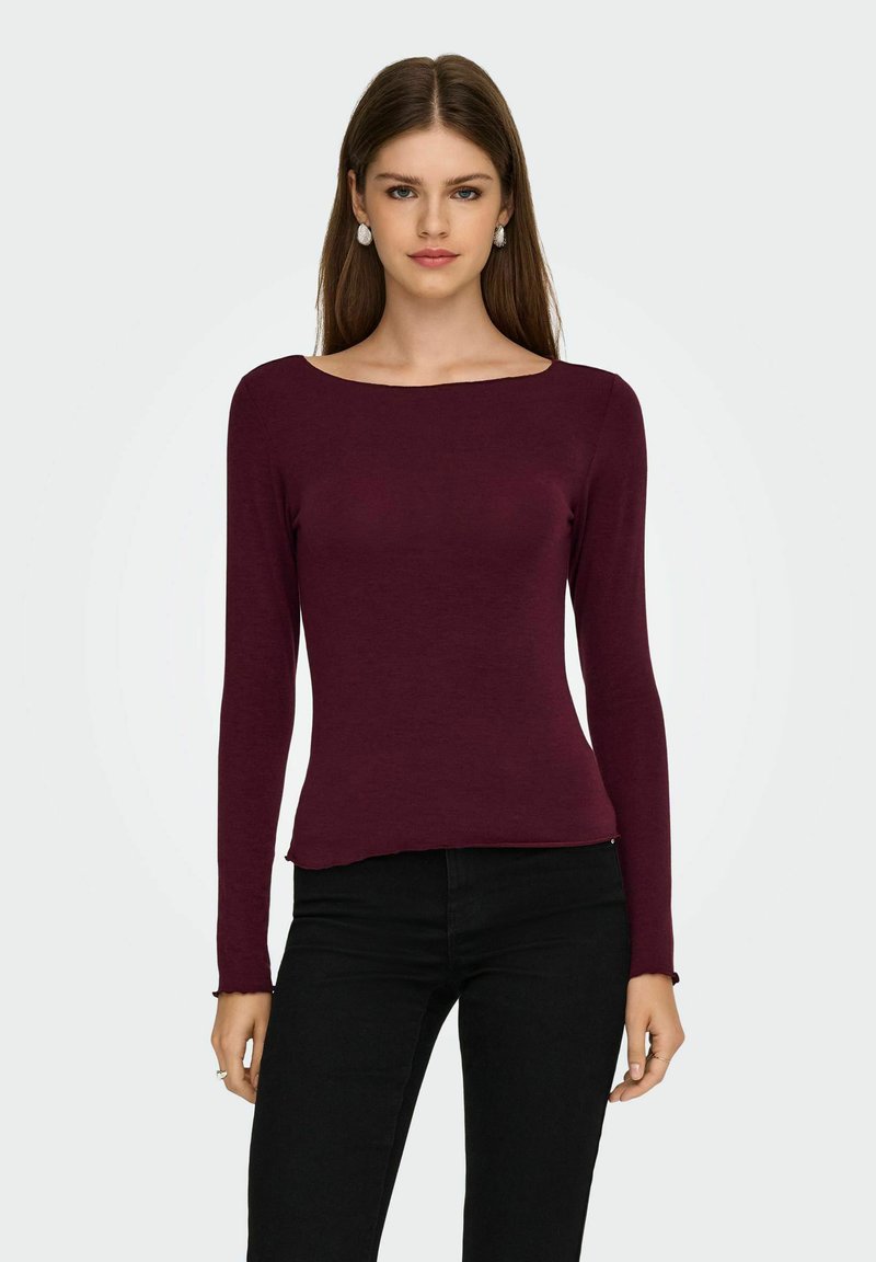Bordeaux lange mouwen top met een brede halslijn, getailleerd ontwerp en licht gescheurde zoom. Gepaard met zwarte skinny jeans. Eenvoudige textuur.