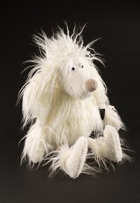 Fluffy white stuffed dog with curly fur, large beige nose, and wide eyes sits against a black background.