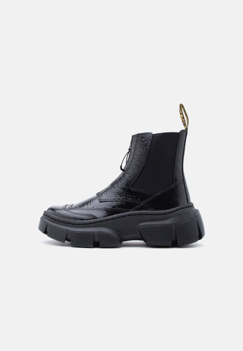 Γυαλιστερό μαύρο χοντρό μποτάκι πλατφόρμας στον αστράγαλο με ελαστικό πλαϊνό πάνελ και θηλιά έλξης σε λευκό φόντο.