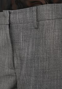 Γκρι παντελόνι με σχέδιο ψαροκόκκαλο και μαλακή υφή, με επίπεδη μπροστινή όψη και μικρή τσέπη στη μέση.