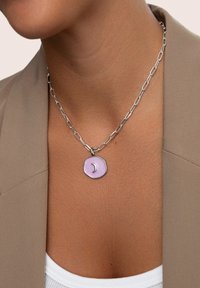 Zilveren ketting met een schakeldesign; voorzien van een ronde, lichtpaarse hanger met een halve maan-vorm in het midden en een onregelmatige rand.