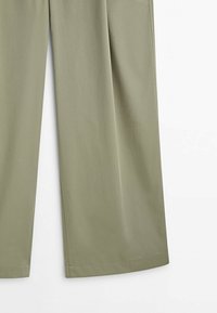Pantalons larges vert olive clair en tissu lisse, présentant des coutures nettes et une silhouette droite. Aucune motif ou accent visible.