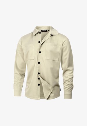 Beige knappskjorte laget av teksturert stoff, med krage, to brystlommer og sorte knapper foran.