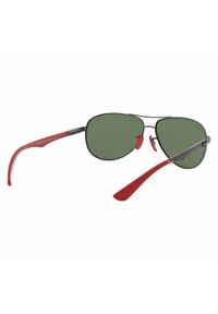 Occhiali da sole aviator con lenti tintate di verde, montatura in metallo nero e bracci in plastica rossa; le caratteristiche includono naselli regolabili e un design elegante.