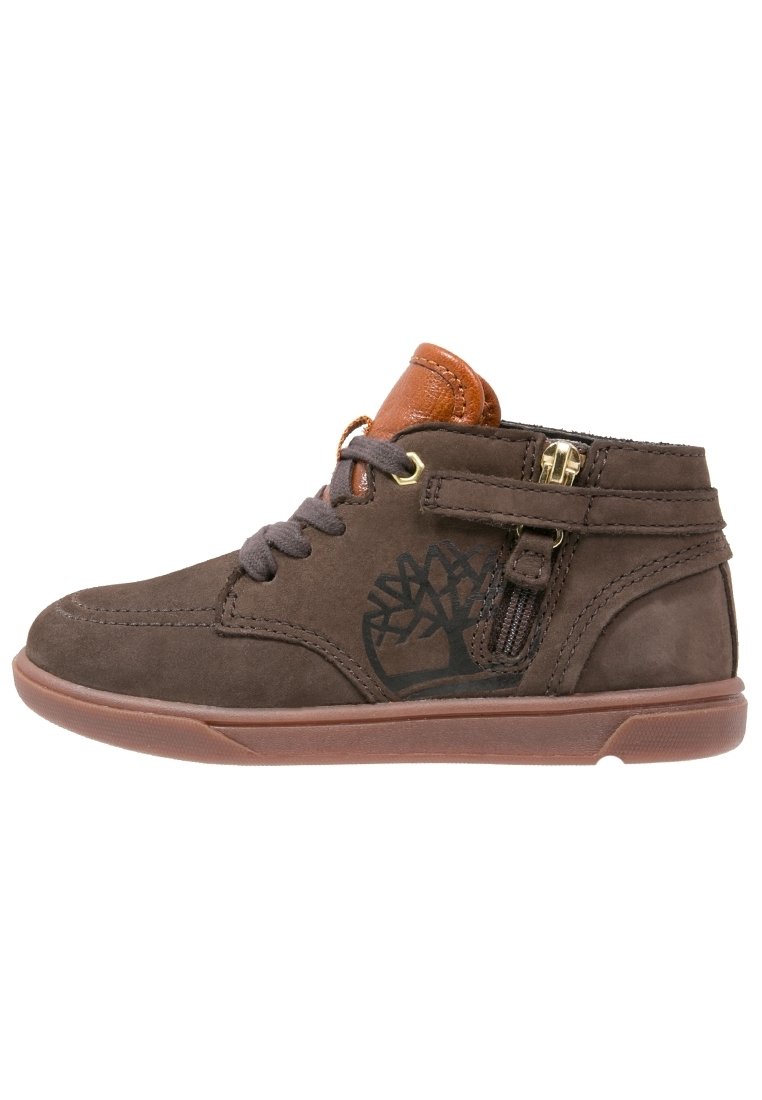 Zapatilla alta de ante marrón con lengüeta acolchada naranja, cremallera lateral, correa, cordones y logo de árbol en el lateral.